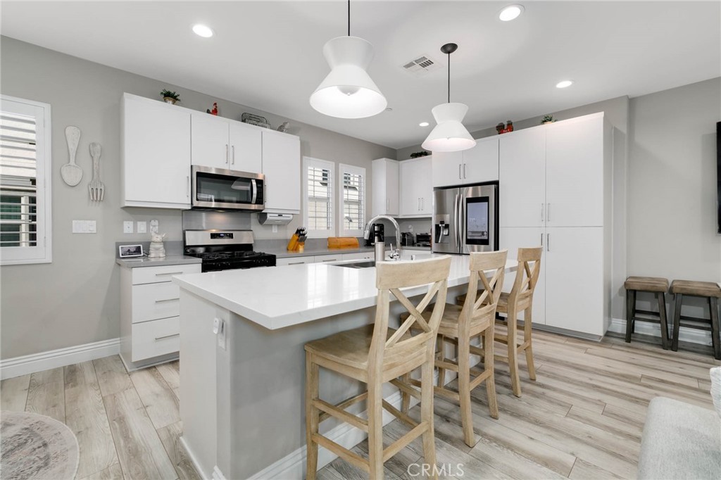 837 Iris Way, Unit C Azusa, CA 91702 - Photo 7 of 38 a kitchen with stainless steel appliances granite countertop a sink a stove a refrigerator cabinets a dining table and chairs