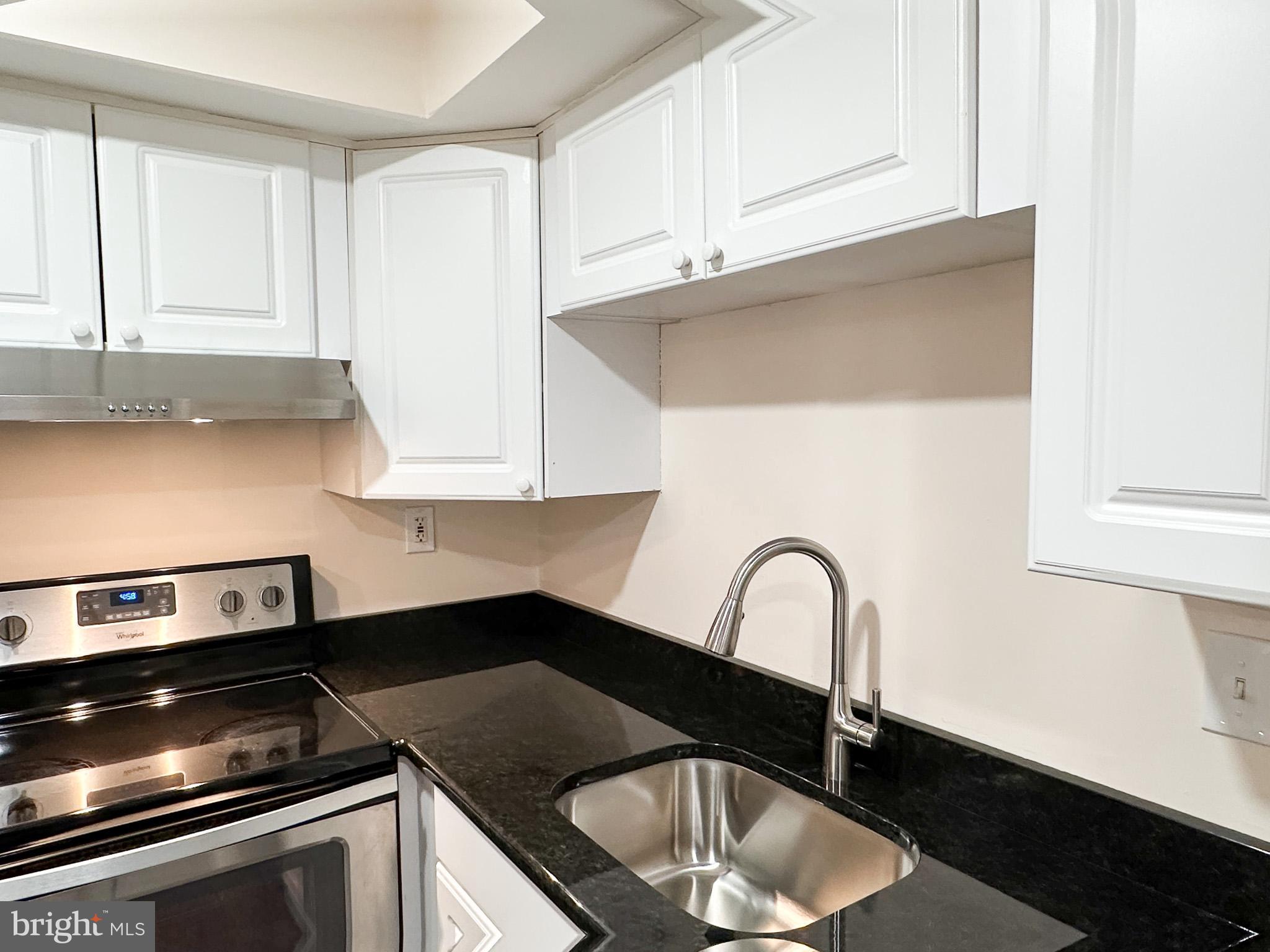 1803 Worthington Drive Exton, PA 19341 - Photo 6 of 27 a kitchen with granite countertop white cabinets and black appliances