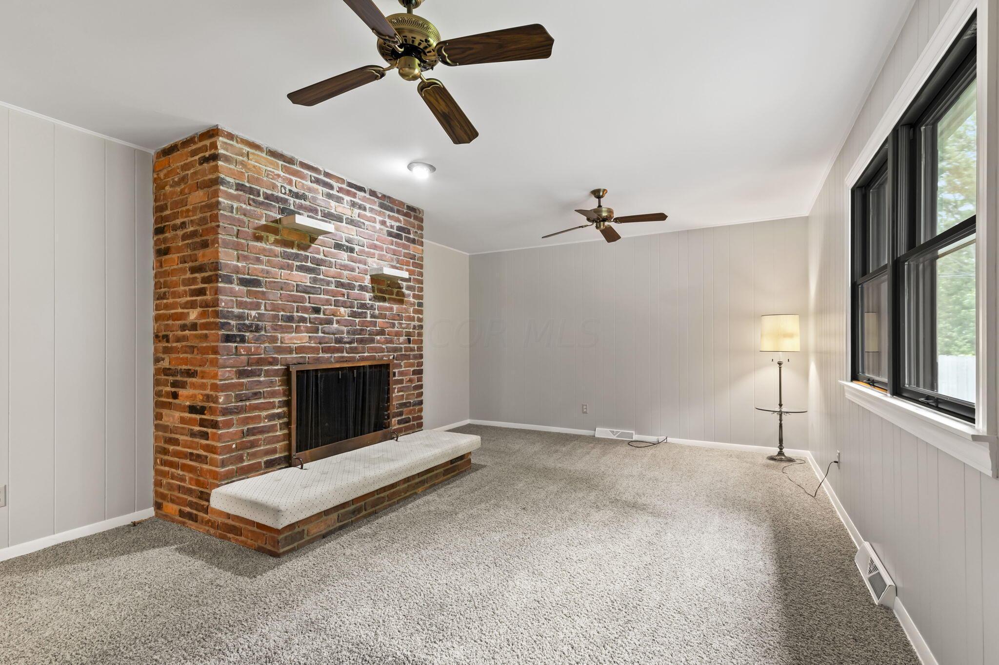999 Birchmont Road Columbus, OH 43220 - Photo 21 of 53 Brick surround fireplace with multiple ceiling fans in the family room. It has freshly painted paneling and beautiful Anderson Windows overlooking the backyard.