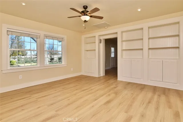 a view of empty room with wooden floor and fan