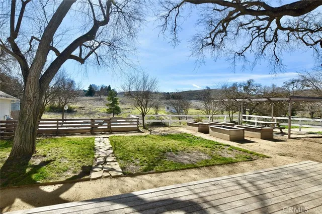 a view of a backyard with lawn chairs under an umbrella