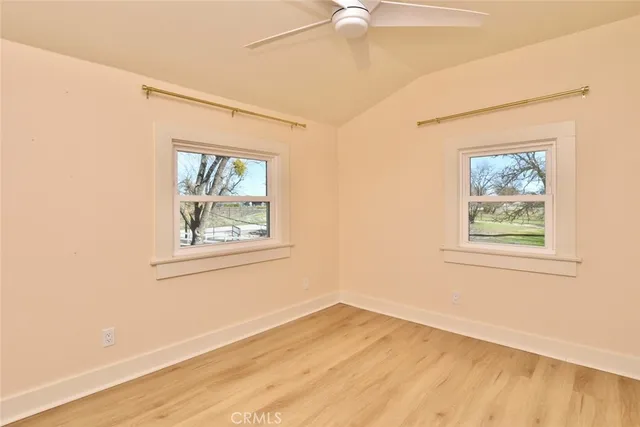 an empty room with wooden floor fan and windows