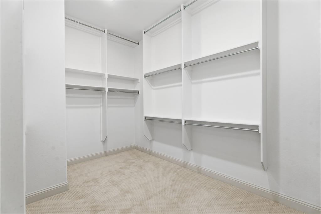1316 Limestone Ridge Road Mansfield, TX 76063 - Photo 21 of 40 Spacious walk-in closet featuring built-in shelving, multiple hanging rods, light-toned carpeting, white walls, and crown molding