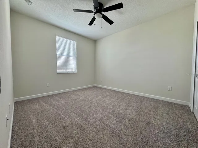 an empty room with a window and a fan