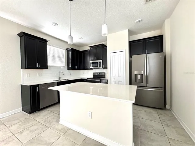 a kitchen with stainless steel appliances granite countertop a refrigerator a stove a sink and a microwave