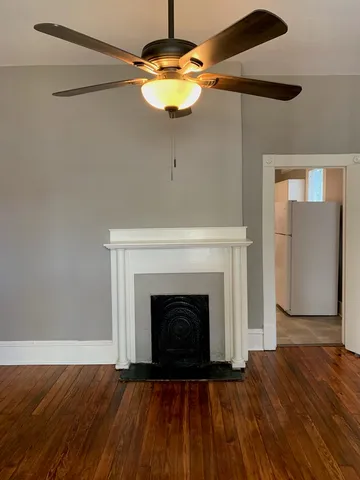 a view of an empty room with wooden floor and a fireplace