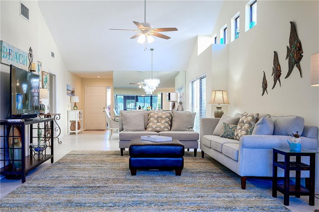833 Reef Point Circle Naples, FL 34108 - Photo 15 of 41 Living area with light tile patterned floors, ceiling fan, a chandelier, and high vaulted ceiling