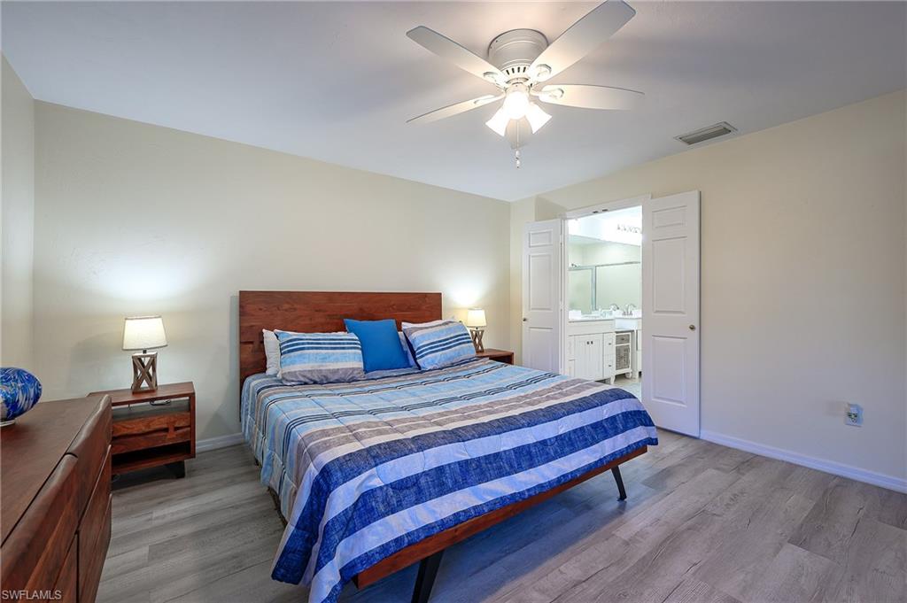 833 Reef Point Circle Naples, FL 34108 - Photo 18 of 41 Bedroom with wood finished floors, ceiling fan, and connected bathroom