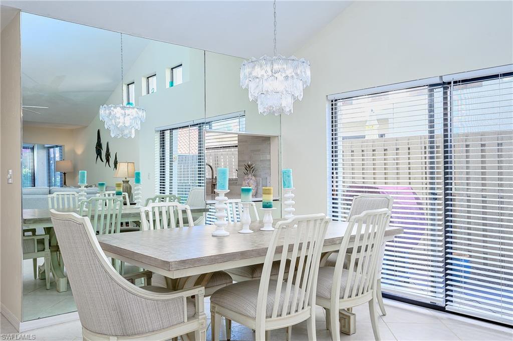 833 Reef Point Circle Naples, FL 34108 - Photo 8 of 41 Dining room with vaulted ceiling, a chandelier, and light tile patterned floors