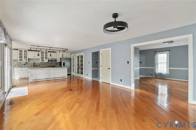 a view of a livingroom with wooden floor and a kitchen
