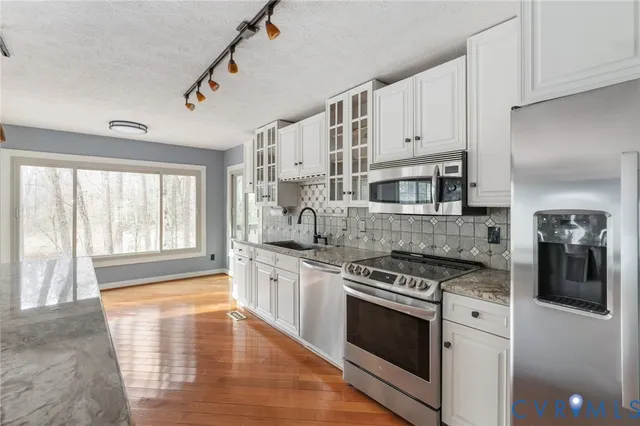 a kitchen with stainless steel appliances white cabinets and a stove top oven