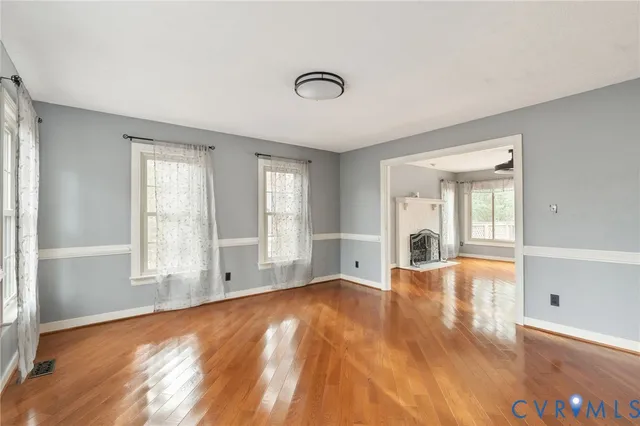 a view of an empty room with window and wooden floor