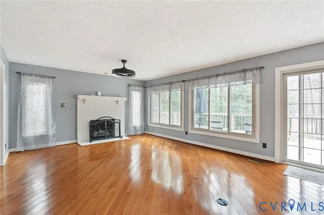 an empty room with fireplace wooden floor and windows