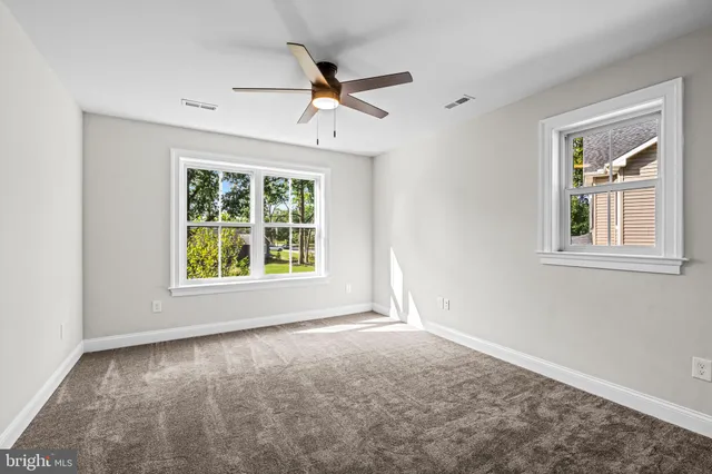 an empty room with windows and ceiling fan