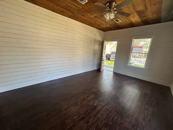 a view of an empty room with wooden floor and a window
