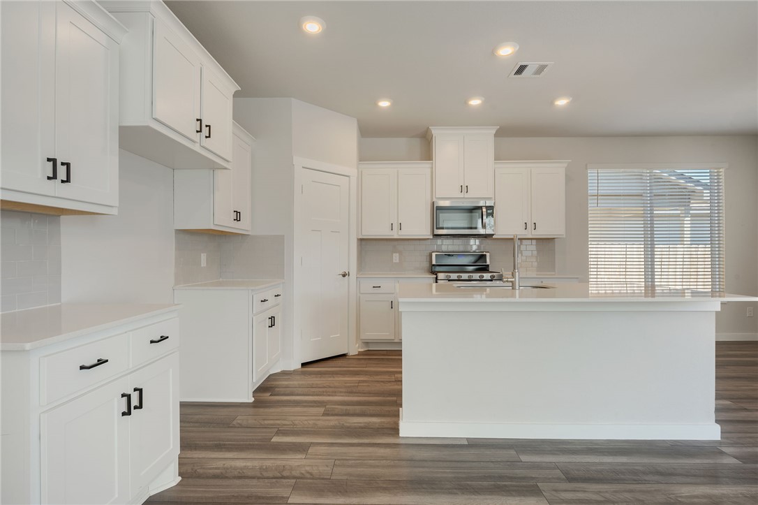 768 Double Mountain Road College Station, TX 77845 - Photo 6 of 28 a kitchen with kitchen island a white counter top space cabinets and stainless steel appliances