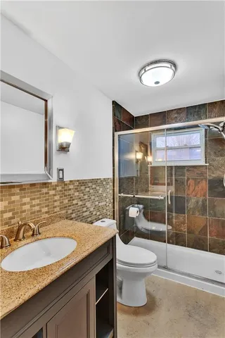 a bathroom with a granite countertop sink toilet and shower