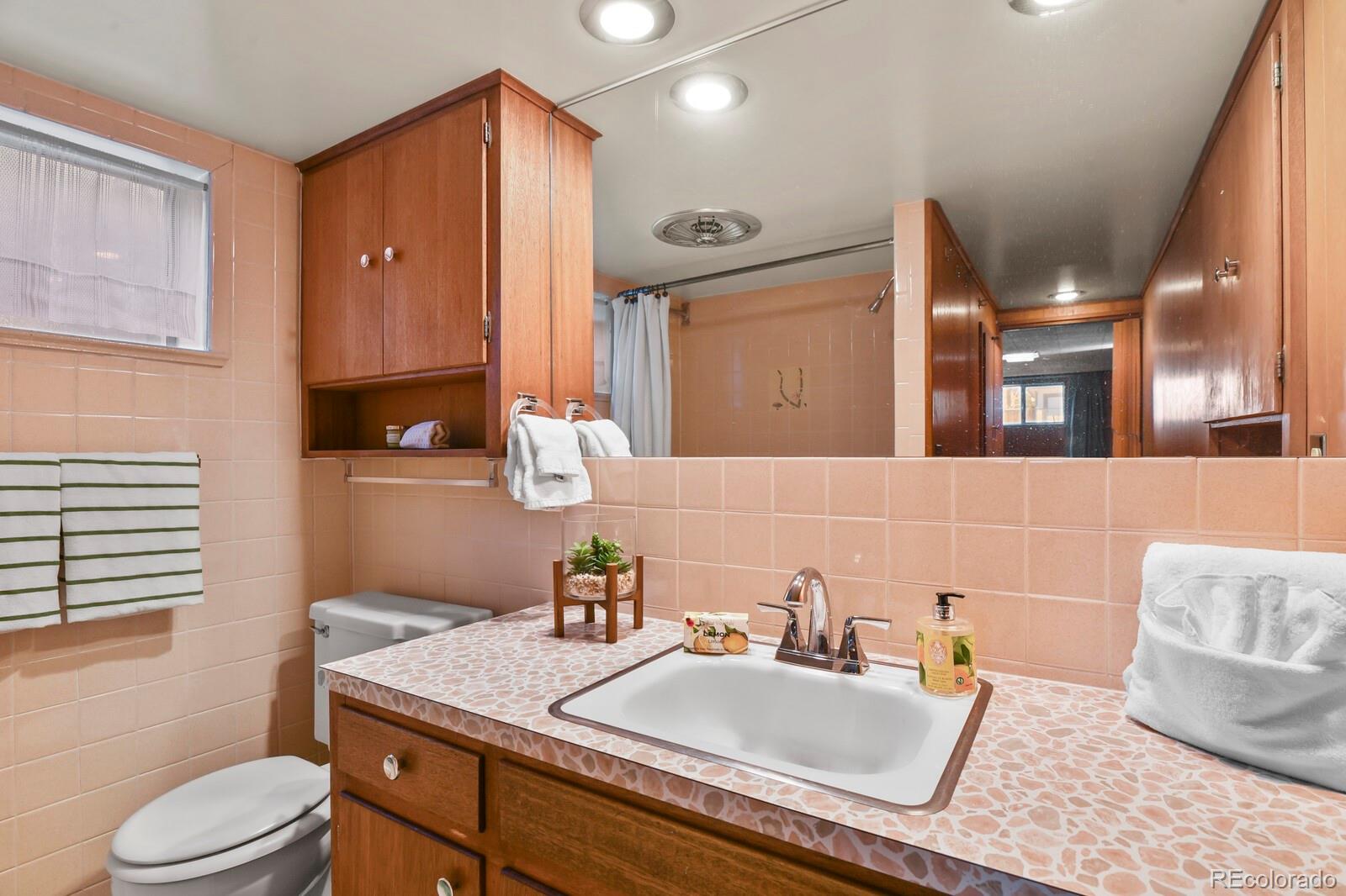 4537 Quitman Street Denver, CO 80212 - Photo 22 of 38 a bathroom with a granite countertop sink a toilet a mirror and vanity