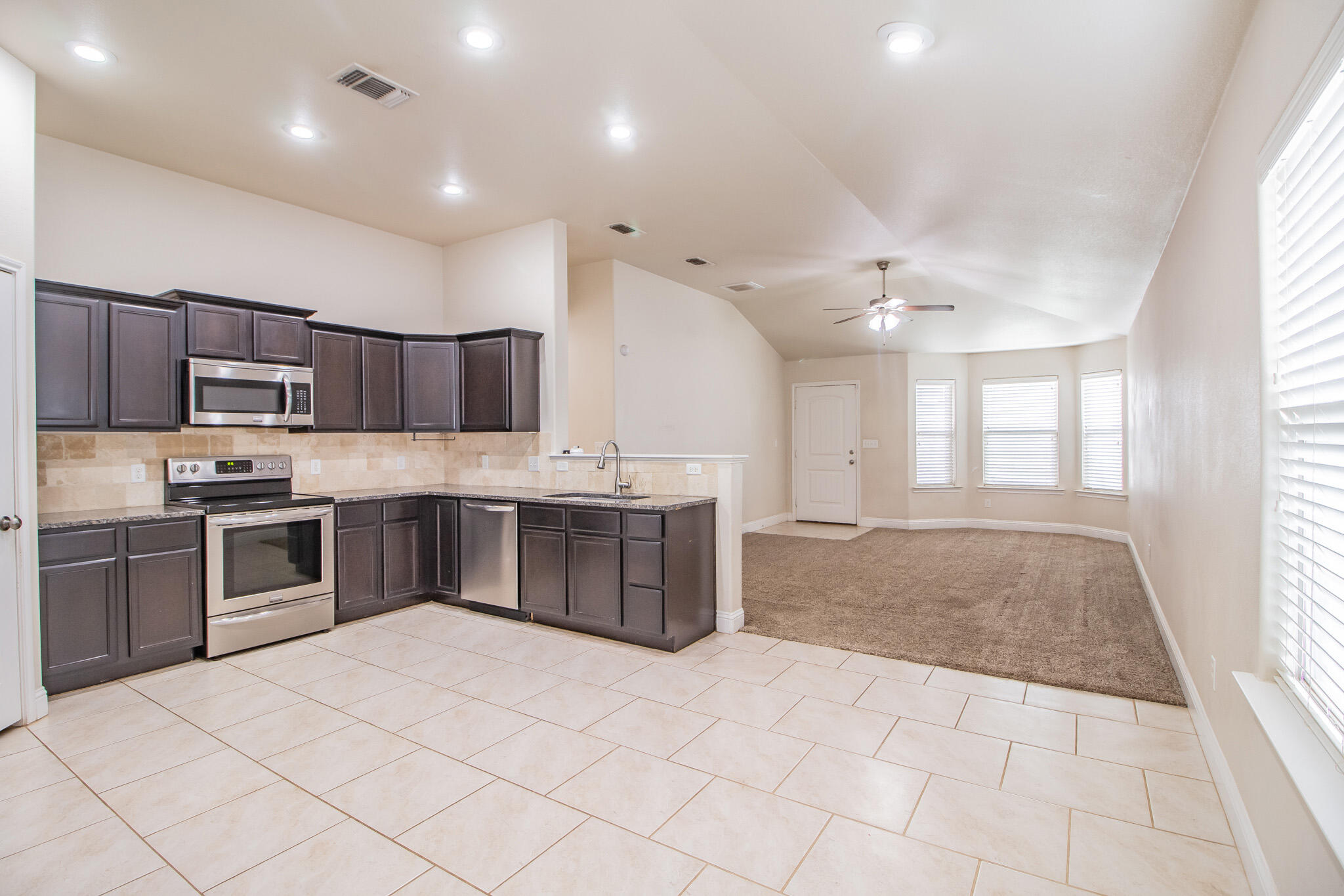 7409 101st Street Lubbock, TX 79424 - Photo 7 of 22 a large kitchen with stainless steel appliances kitchen island granite countertop a sink and cabinets