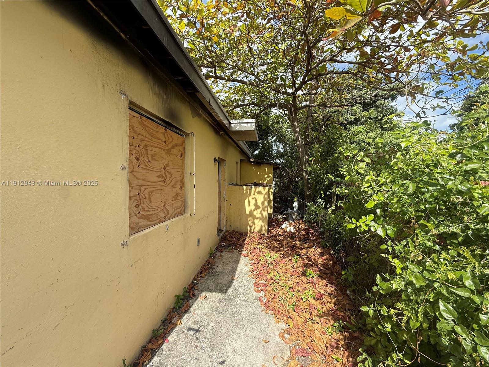 1865 Northwest 70th Street Miami, FL 33147 - Photo 5 of 9 a yellow house with trees in front of it