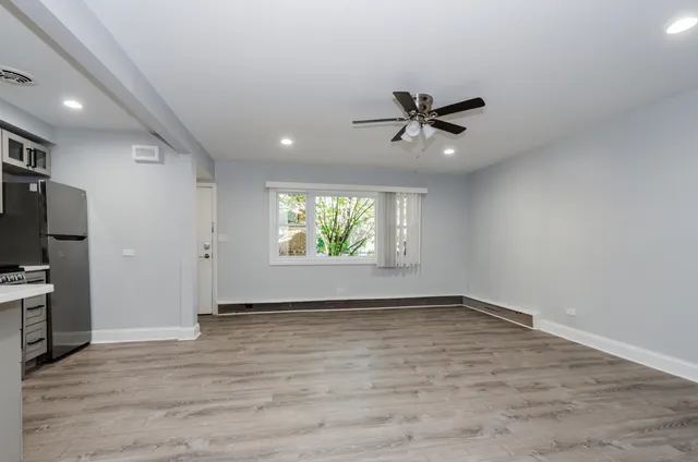 an empty room with window ceiling fan and hardwood floor