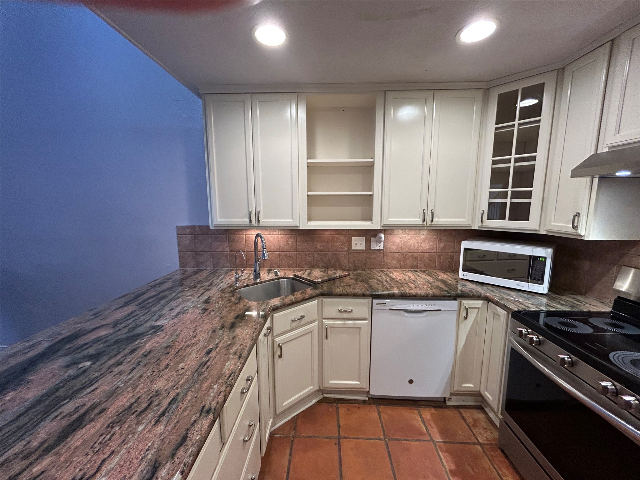 13034 Leader Street, Unit 965 Houston, TX 77072 - Photo 8 of 32 This kitchen features a lazy susan with 2 revolving shelves . Elegant granite countertops and cream cabinetry enhance the space. It includes modern appliances, a corner sink, creating a warm and inviting space.