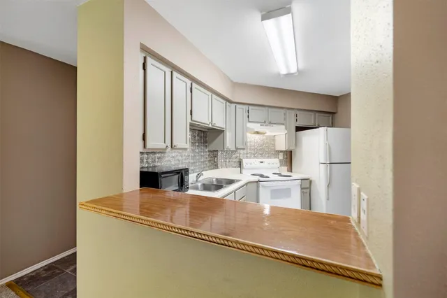 a kitchen with stainless steel appliances granite countertop a refrigerator a stove and a sink