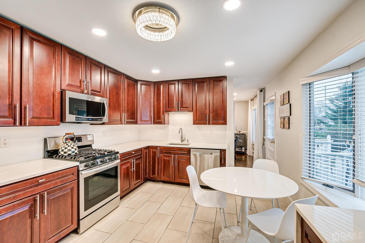 12 Eardley Road Edison, NJ 08817 - Photo 15 of 36 a kitchen with stainless steel appliances granite countertop a stove top oven a sink dishwasher a dining table and chairs with wooden floor