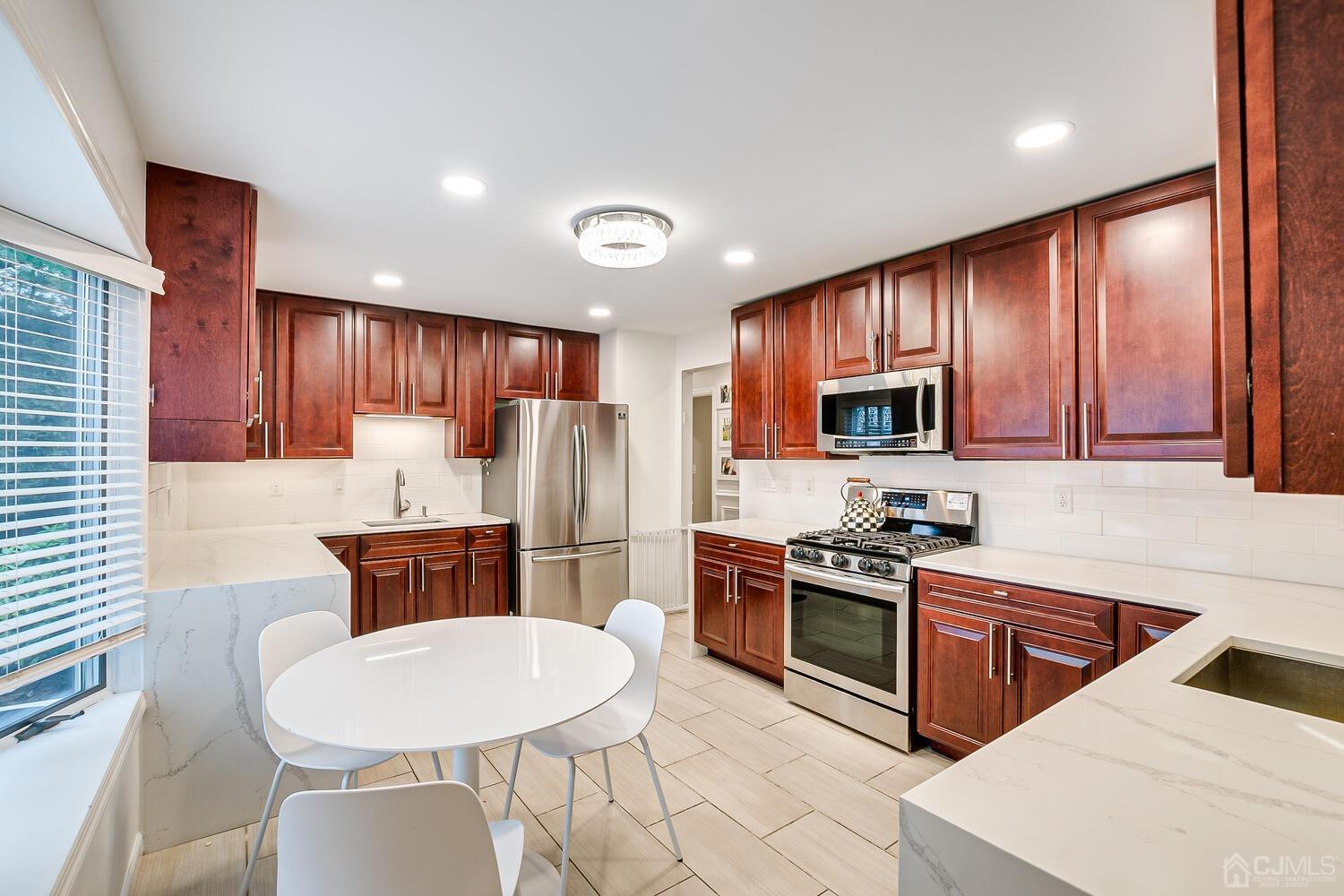 12 Eardley Road Edison, NJ 08817 - Photo 16 of 36 a kitchen with stainless steel appliances a stove a sink a refrigerator white cabinets a dining table and chairs