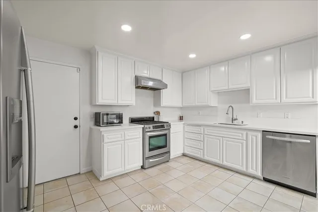 a kitchen with stainless steel appliances granite countertop a stove a refrigerator and a cabinets