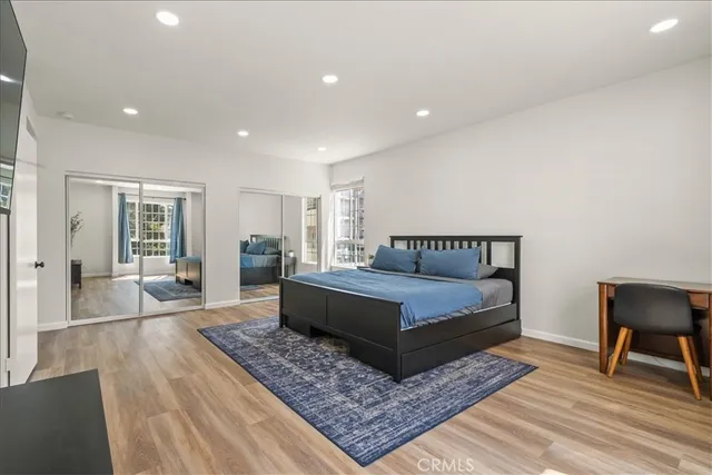 a bedroom with a large bed rug and wooden floor