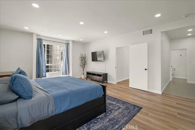 a spacious bedroom with a bed and a flat screen television