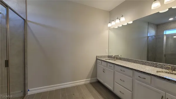 a bathroom with a granite countertop sink a light fixture and a mirror