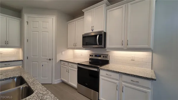 a kitchen with granite countertop white cabinets and black appliances