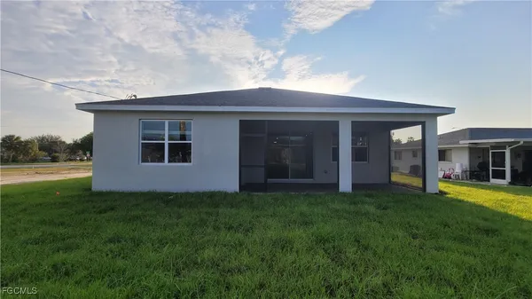 a view of a house with a yard and a large tree