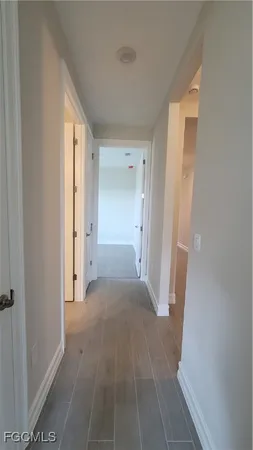 a view of a hallway with wooden floor and a bathroom