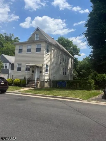 a front view of a house with a yard and trees