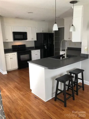 a kitchen with kitchen island a counter space a sink appliances and cabinets