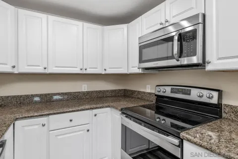 a kitchen with granite countertop white cabinets and stainless steel appliances