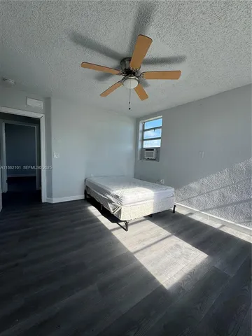 an empty room with wooden floor ceiling fan and windows