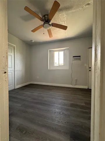 an empty room with wooden floor fan and windows