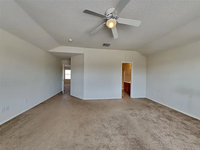 an empty room with a ceiling fan and carpet