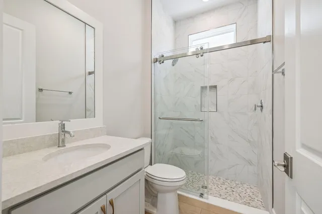 a bathroom with a granite countertop sink a toilet and a mirror