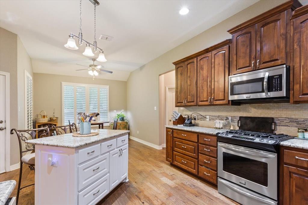 128 Creek Ridge Drive Waco, TX 76708 - Photo 14 of 40 Kitchen featuring stainless steel appliances, tasteful backsplash, a kitchen bar, a ceiling fan, and a kitchen island