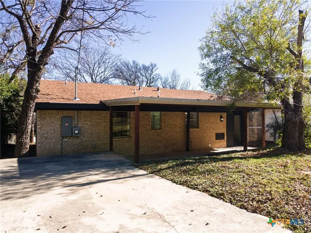 a view of a house with a yard and large tree