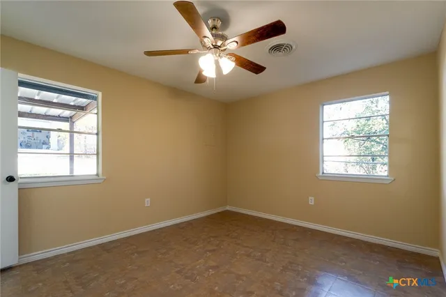 an empty room with a window and a ceiling fan