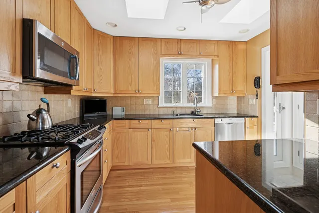 a kitchen with stainless steel appliances granite countertop a stove a sink and a microwave