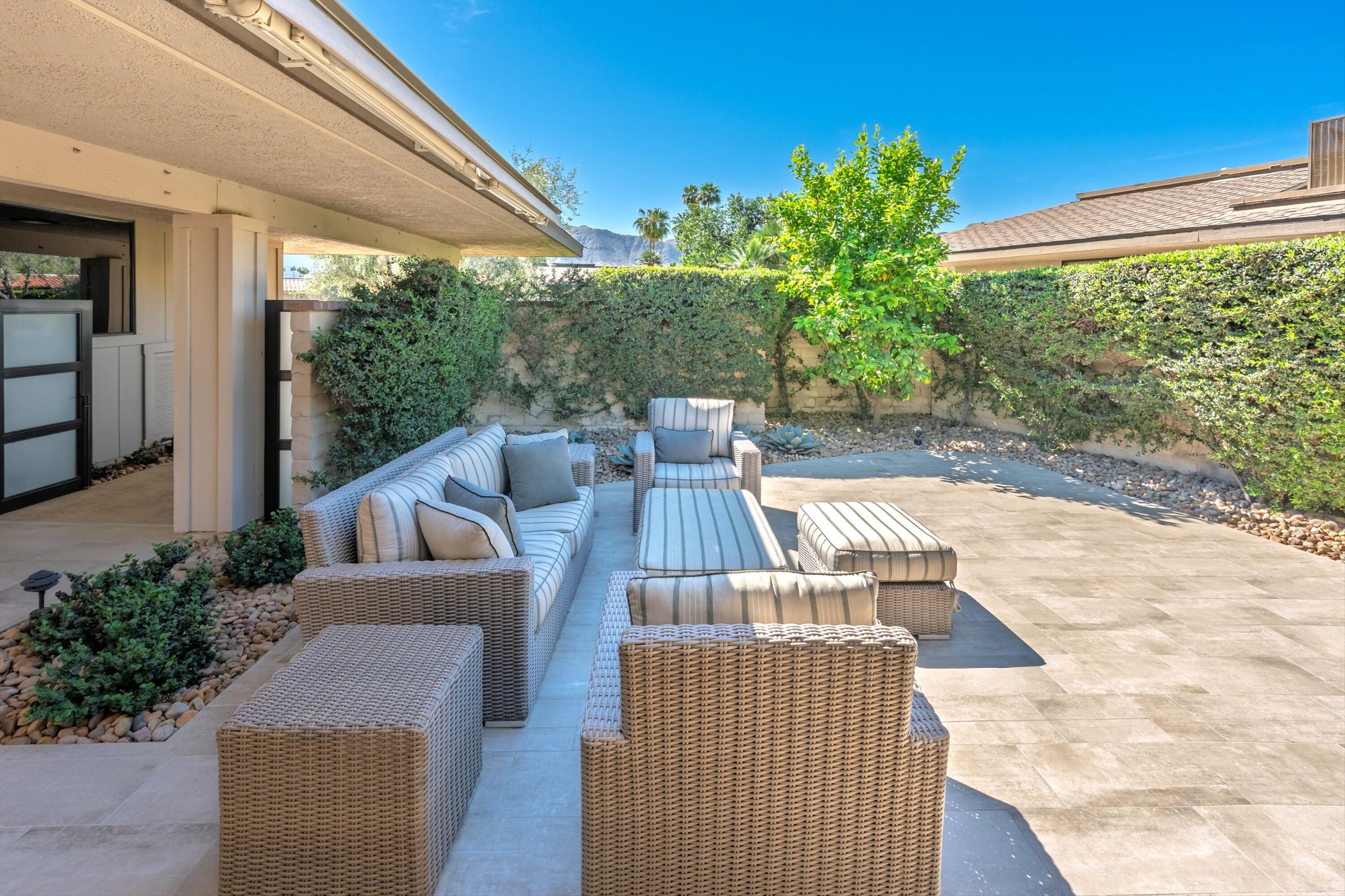 3 Barnard Court Rancho Mirage, CA 92270 - Photo 36 of 47 a view of a patio with couches chairs potted plants and floor to ceiling window