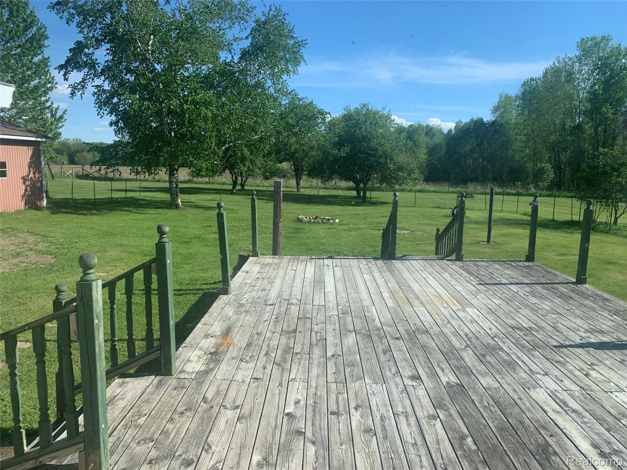 3494 Castle Road North Branch, MI 48461 - Photo 9 of 22 Expansive wood-finish deck with green balusters and posts, overlooking a large grassy area
