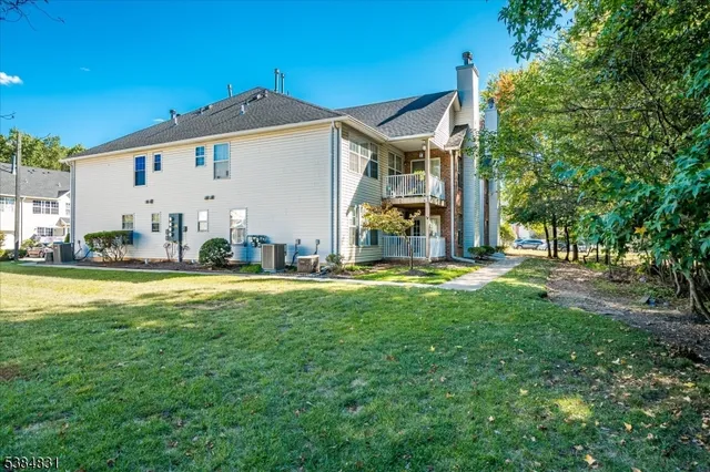 a view of a white house with a big yard and large trees